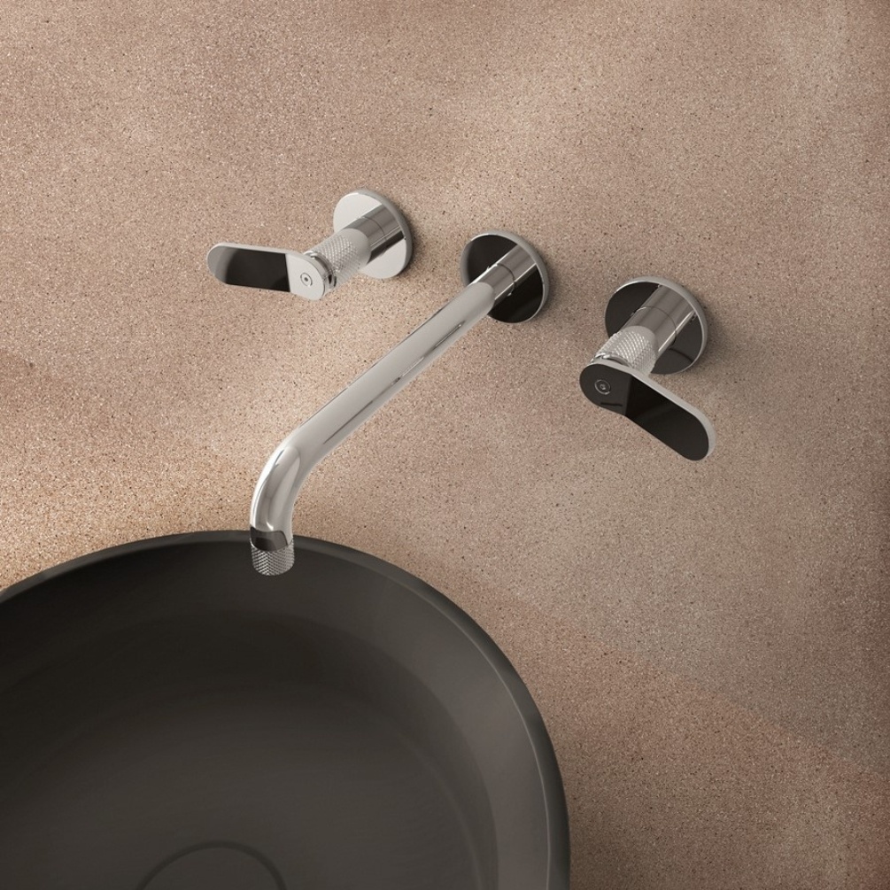 Lifestyle image of the Crosswater Calix Chrome 3 Tap Hole Wall Mounted Mixer Tap installed above a black countertop basin